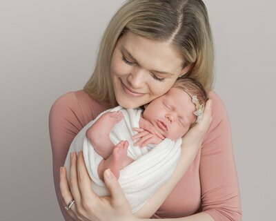 mom wearing pink dress holding baby newborn girl