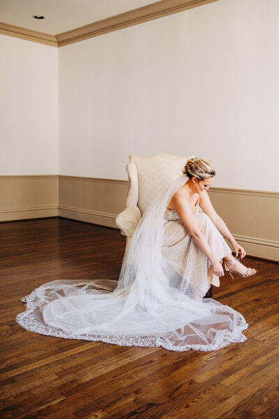 bride putting her shoes on during bridal portraits
