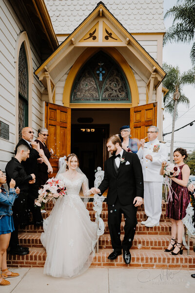 bride and groom walking down the steps of a church while smiling