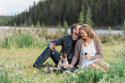 couple with small dog sitting in grass next to a road