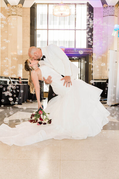 Image of groom dipping bride under cascading bubbles inside the front doors of The Carlisle Room, Dallas, Tx.