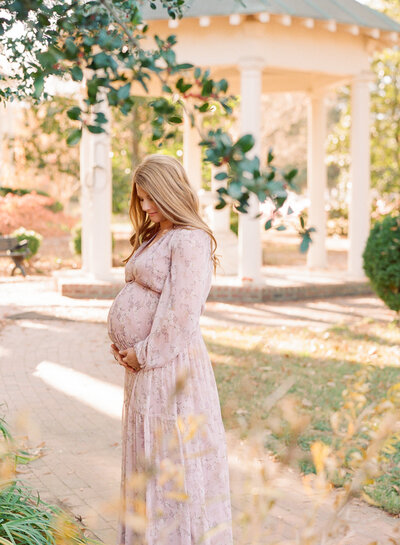 Mom holding newborn baby and smiling at him while he holds her finger during their newborn photography session in Raleigh NC. Photographed by Raleigh Newborn photographers A.J. Dunlap Photography.