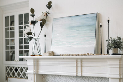 a calming painting of the ocean sitting on a mantle