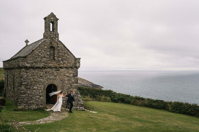 A bride and groom leaving a seaside church