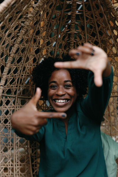 A woman smiling with her hands outstretched in front of her face.