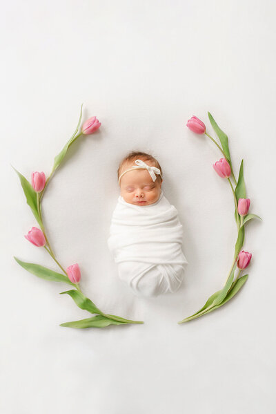 newborn baby surrounded by tulips on white blanket by Newborn photographer Boston