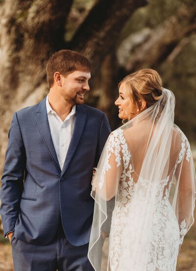 Lauren and her husband on their wedding day beneath Southern oak trees. Tailored Oasis Travel Co.