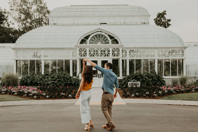Man spins his fiance under his arm during engagement session at Volunteer Park