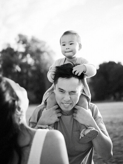 Toddler on her dad's shoulders playing with his hair at Jericho Beach. 