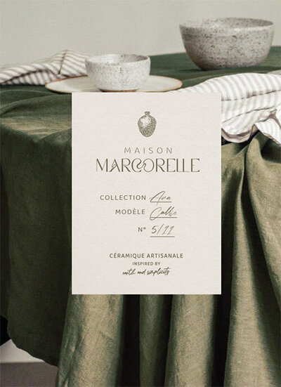 Etiquette Maison marcorelle crée par le Studio Youmé, spécialiste en image de marque en Vendée. Fond représentant une table dressée avec une nappe verte et de la vaisselle.