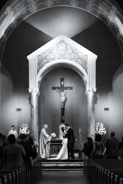 bride and groom kiss during a Catholic wedding ceremony at Holy Rosary Church in Houston Texas by Swish and Click Photography