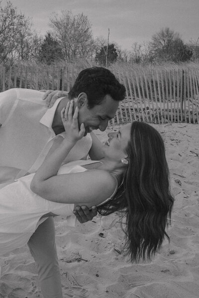 Man dips his girl while leaning in for a kiss on the beach in Maryland 