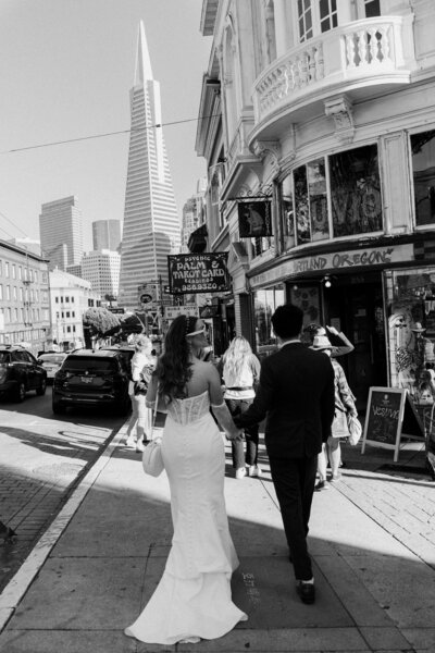 newlyweds walking down city sidewalk