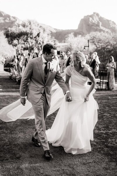 Bride and groom laughing at each other during the recessional of their El Chorro wedding.