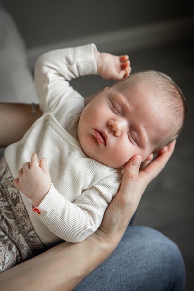 Baby ligt in moeders handen tijdens fotoshoot.