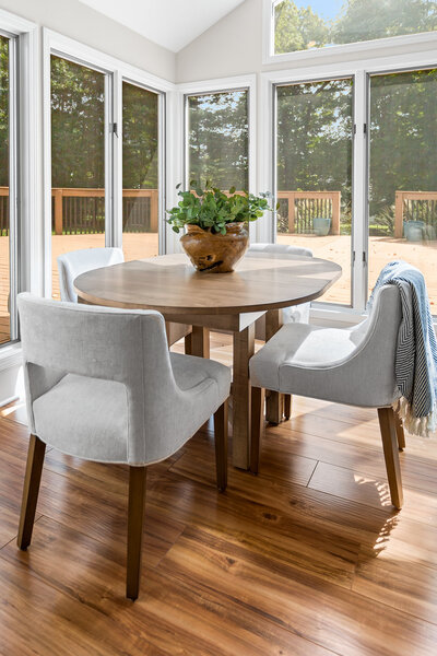 Dark wood floor and dark wood table with light gray chairs overlooking back yard