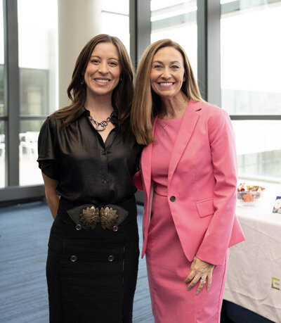 Two women standing one in pink suit