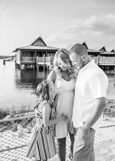 Black and white photo of family at the beach of Disney's polynesian resort, hugging and laughing