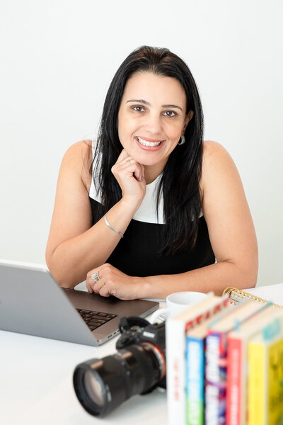 photo of a brand photographer in her desk with laptop, camera and favorite books