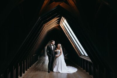 A bride and groom standing under a low ceiling in a heritage buliding with a skylight.