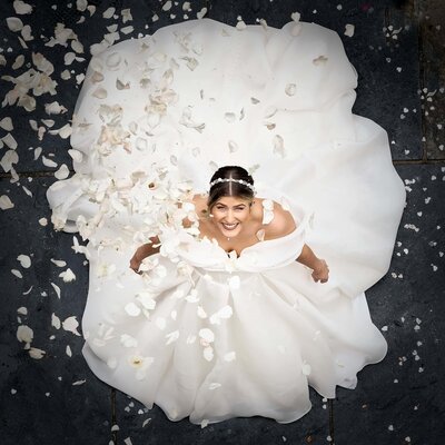 bride looking up at camera as confetti is thrown over her