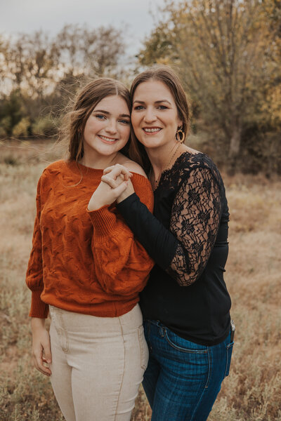 A mother and daughter are side-by-side, face-to-face, close to the camera, smiling