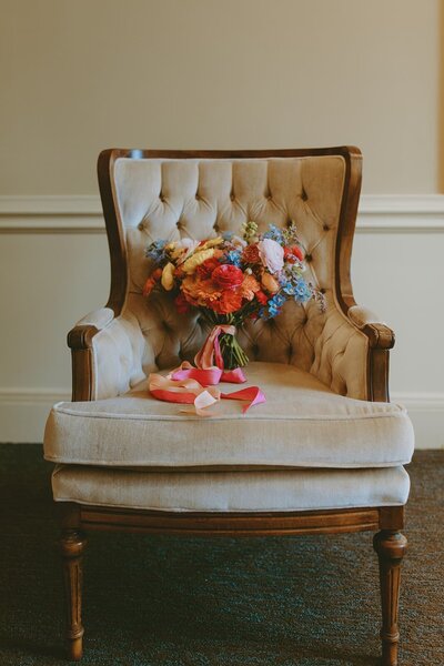 Colorful bouquet of flowers sits on cream colors vintage chair