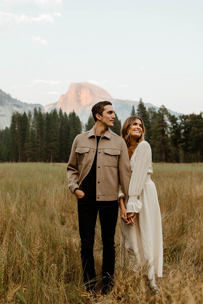 Engagement shot in front of mountains couple holding hands