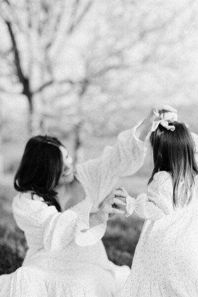 mom twirls daughter around outside as she laughs