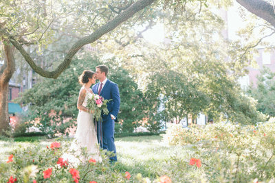 a couple poses beneath a tree at their wedding in Savannah