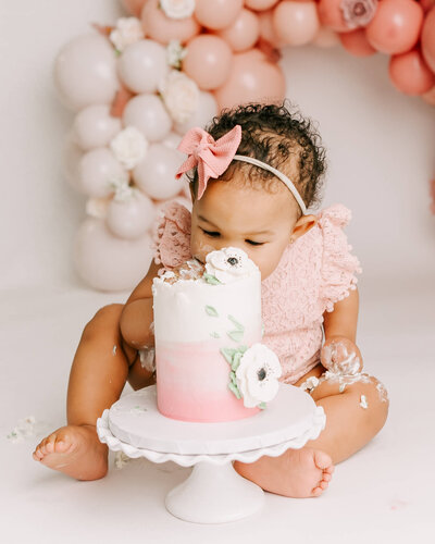 One year old baby girl with smashed cake in front of pumpkins for her first birthday pictures in Portland Studio by portland milestone photographer Ann Marshall