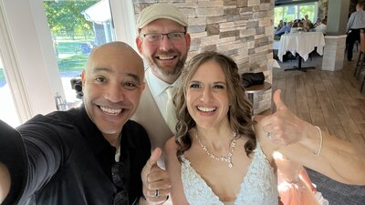 wedding videographer ariel poses for photo with st cloud couple. groom is wearing a hat