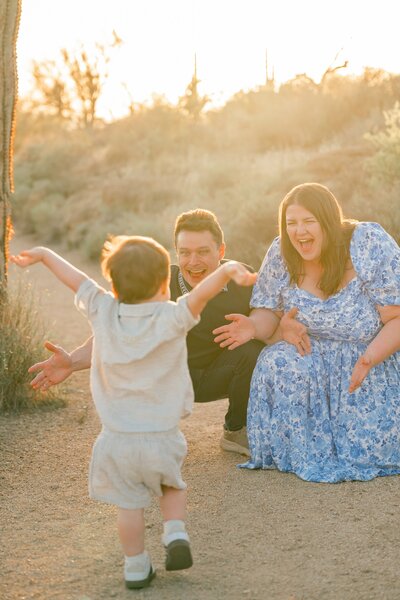 little boy running towards mother and father with arms streched out wide in the arizona desert