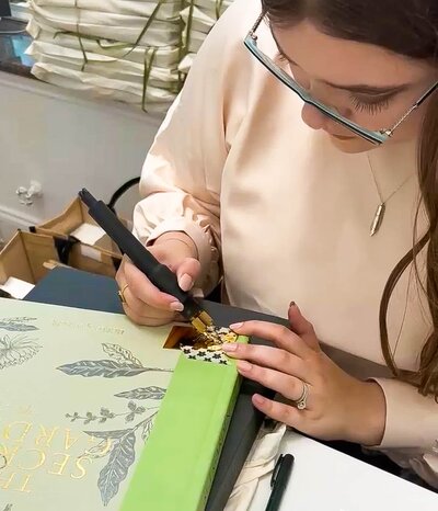 Tampa engraving artist Emily Pellegrino hand embossing green leather book covers in gold calligraphy foil