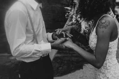 side angle of bride and groom walking away, holding each other's hands while carrying a bottom of champage