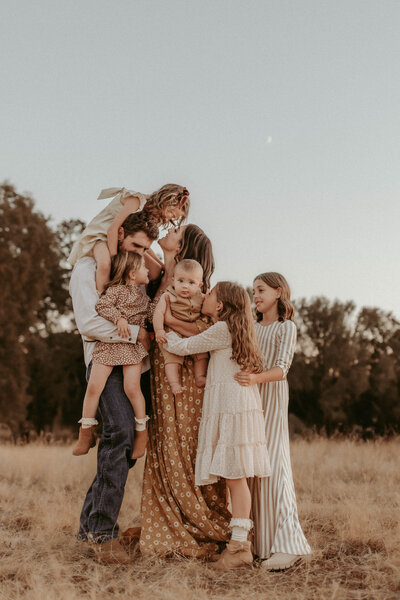 A family of seven in gorgeous nuetral clothing holds each other close at sunset in El Dorado Hills, CA. 