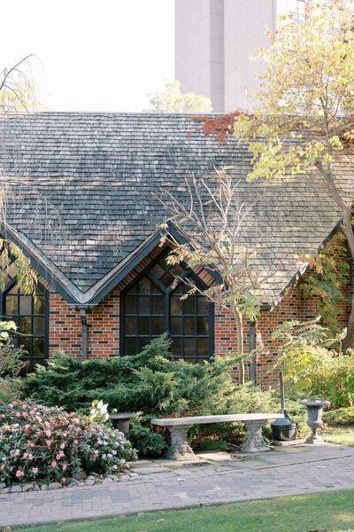Brick cottage facade and garden bench surrounded by greenery, atmospheric photo of Toronto wedding location