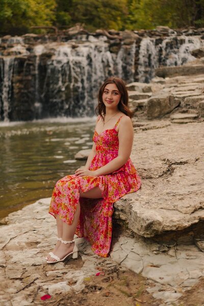 girl posing next to waterfall for senior portraits in dallas