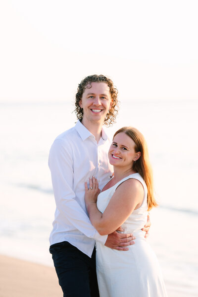 couple arm and arm smiling at the camera during their nauset light beach sunrise engagement session captured by cape cod photographer meghan lynch