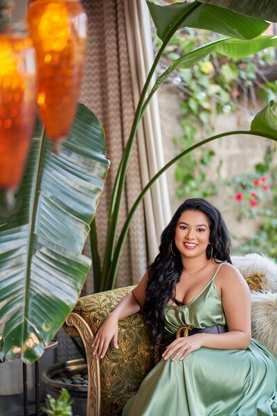 Women in a green dress sitting in a garden under palm leaves