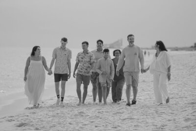 Family photo of 8 people walking on the beach couples holding hands and everyone chatting with each other