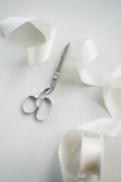 Creamy white ribbon sitting beside vintage silver scissors