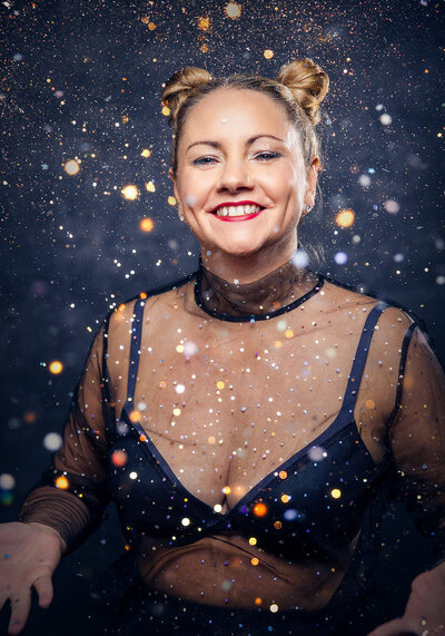woman in her 50s throwing glitter in the air and smiling. Taken for the 40 over 40 project by Norwich womens photographer Claire Howes. 