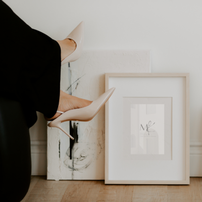 Woman with white heels lounging next to modern framed art, reflecting client confidence and elevated brand experience