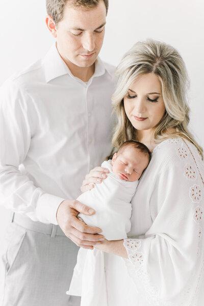 Light and airy newborn photo of parents with baby.