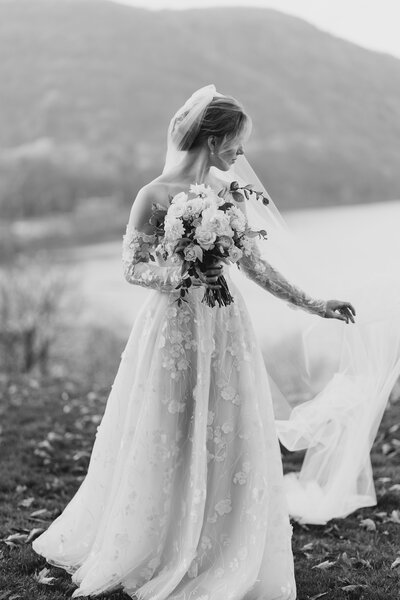 Black and white portrait of bride holding her veil and bouquet