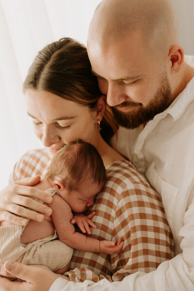 New parents embracing their newborn baby during a cozy and heartfelt family photography session in Sydney