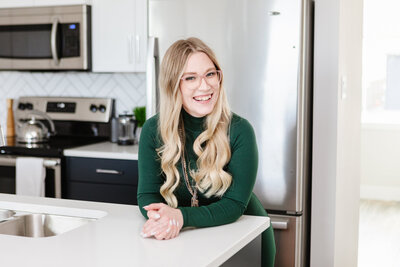 Realtor Tamara Rzan leaning on the counter of a pristine white kitchen