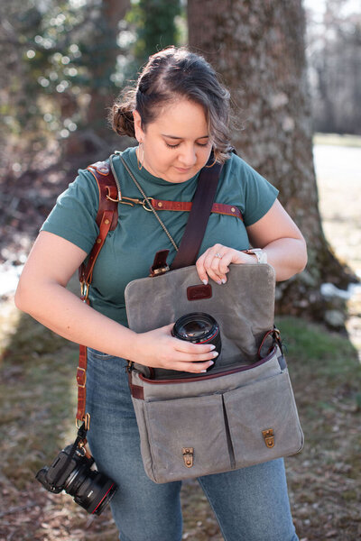 woman grabbing camera equipment out of a messenger bag