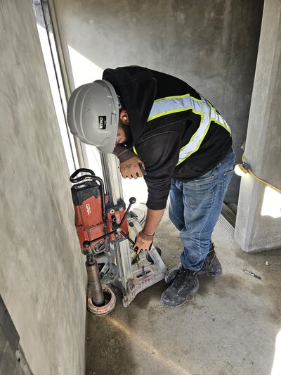 An operator operating a coring drill to core through the concrete slab. 
